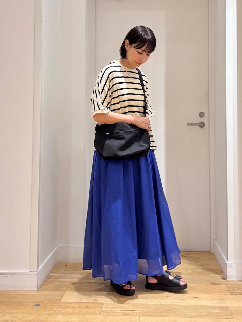 ブルー系のスカート、ブラック系のサンダル、ブラック系のショルダーバッグを着用したレディースの夏コーディネートの3枚目の写真