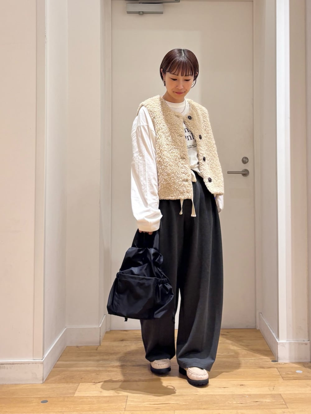ベージュ系のダウンベスト、グレー系のその他パンツ、ホワイト系のTシャツ/カットソーを着用したレディースの秋コーディネートの5枚目の写真