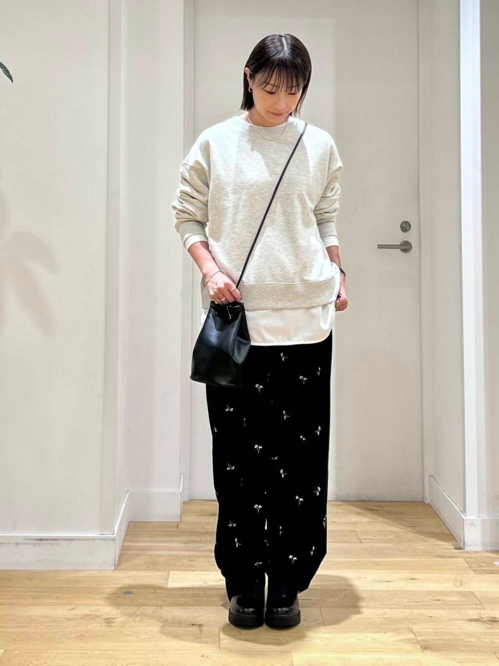 ベージュ系のスウェット、ブラック系のショルダーバッグ、ホワイト系のTシャツ/カットソーを着用したレディースの秋コーディネートの2枚目の写真