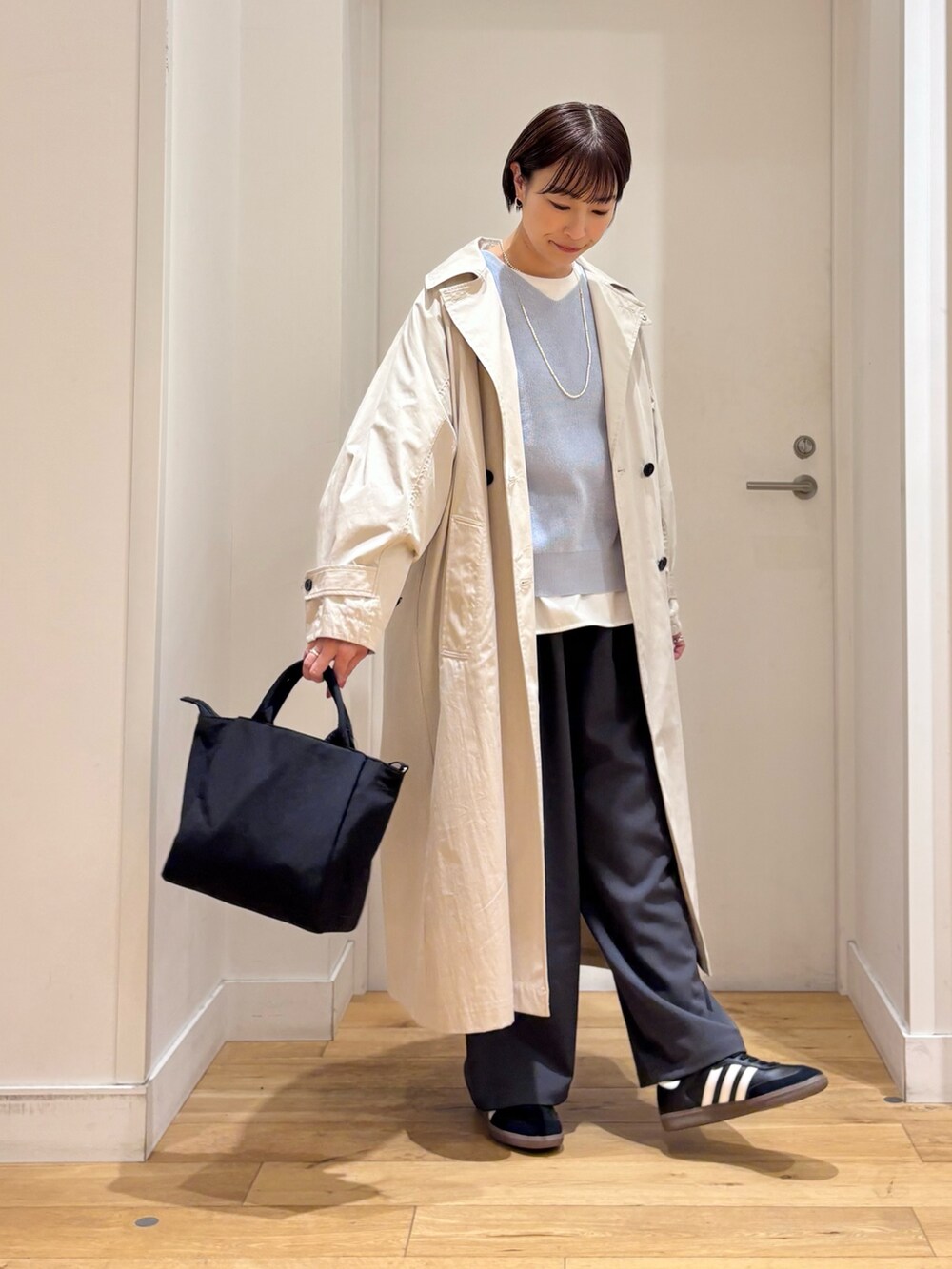 ブルー系のニット/セーター、ホワイト系のTシャツ/カットソー、ベージュ系のトレンチコートを着用したレディースの春コーディネートの5枚目の写真