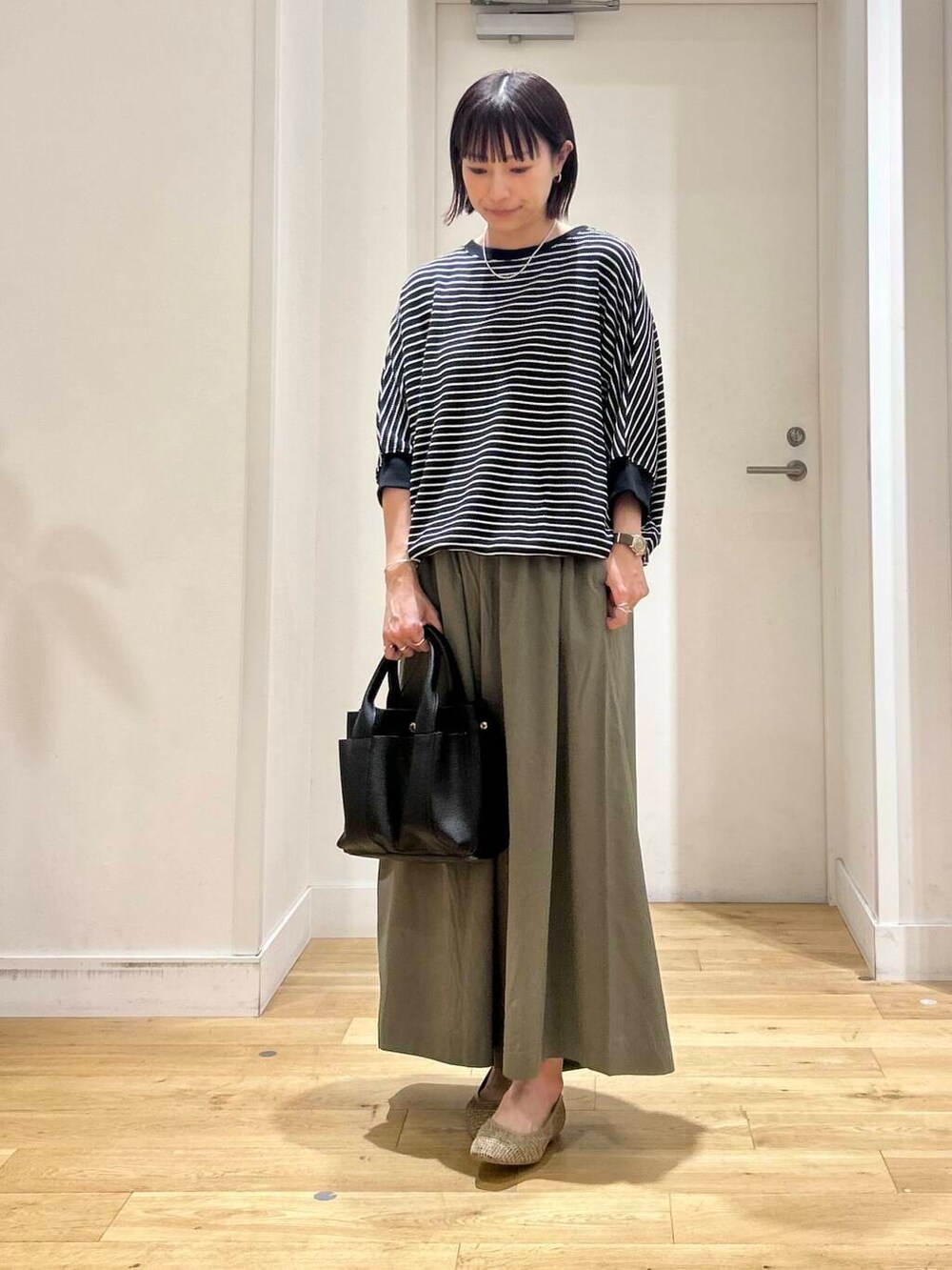 ブラック系のトートバッグ、グリーン系のその他パンツ、ベージュ系のパンプスを着用したレディースの夏コーディネートの3枚目の写真