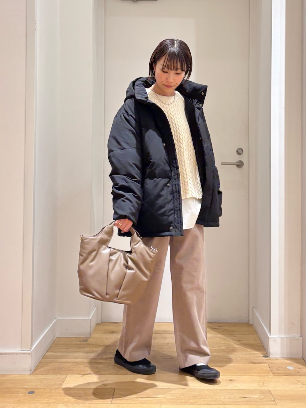 ブラック系のダウンジャケット/コート、ベージュ系のニット/セーター、ホワイト系のシャツ/ブラウスを着用したレディースの冬コーディネートの3枚目の写真