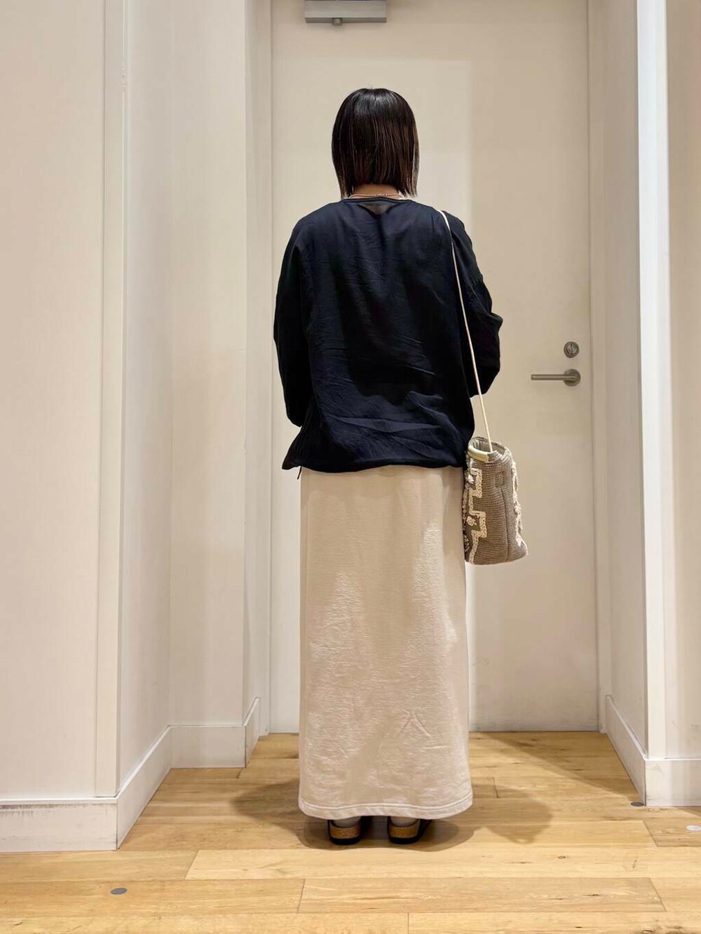 グレー系のショルダーバッグ、ブラック系のチュニック、グレー系のサンダルを着用したレディースの春コーディネートの6枚目の写真