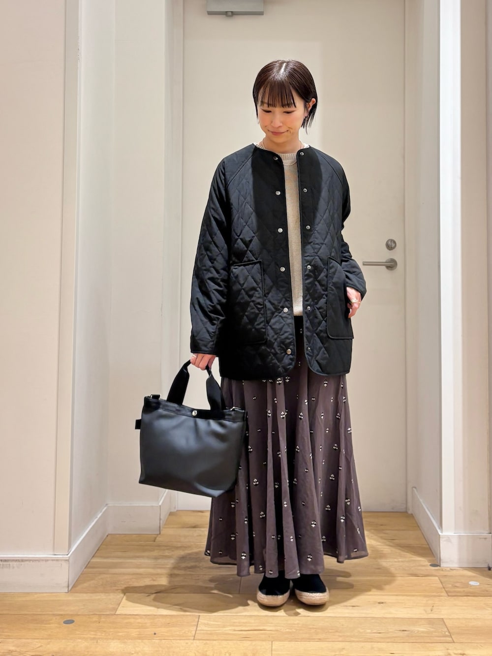 ブラック系のハンドバッグ、グレー系のニット/セーター、グレー系のスカートを着用したレディースの春コーディネートの3枚目の写真