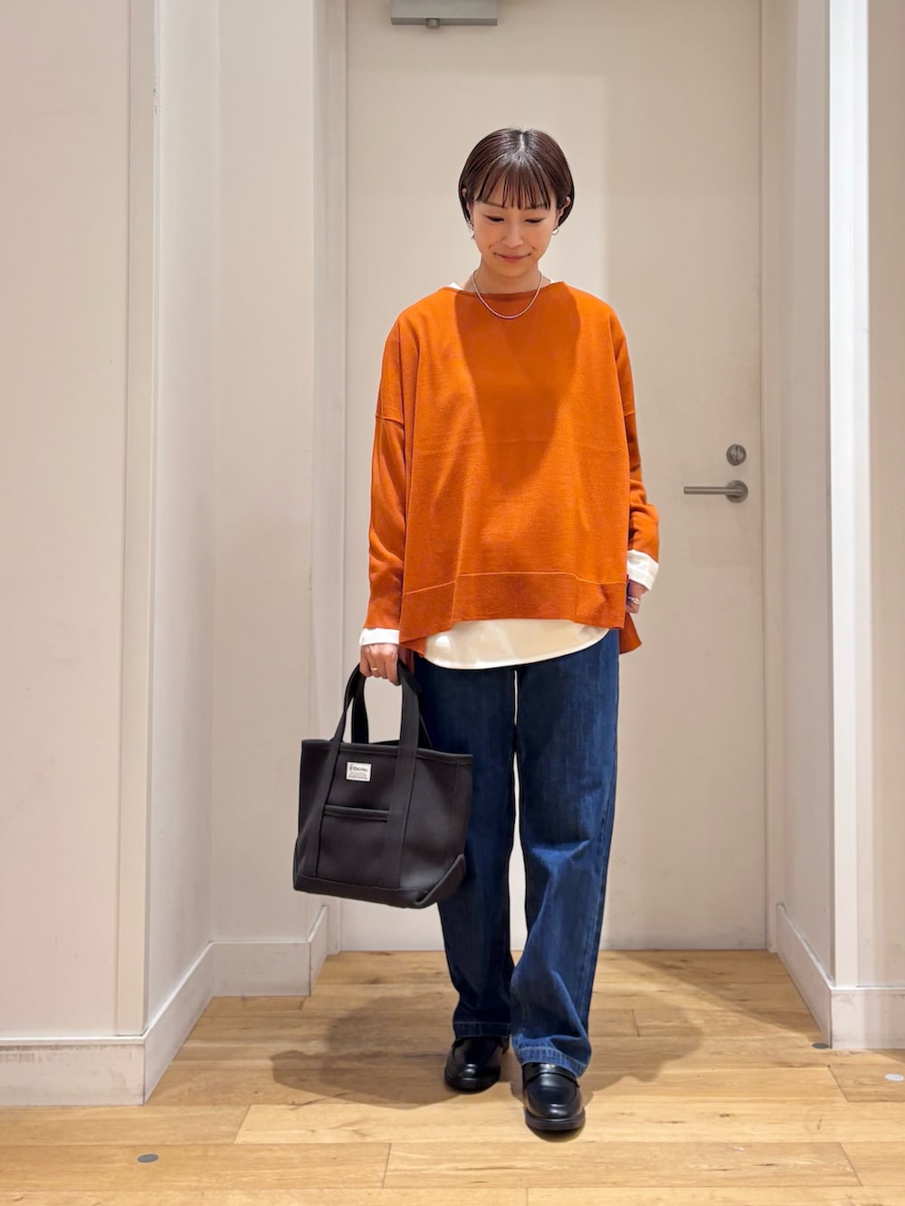 グレー系のブルゾン、オレンジ系のニット/セーター、ホワイト系のTシャツ/カットソーを着用したレディースの秋コーディネートの6枚目の写真