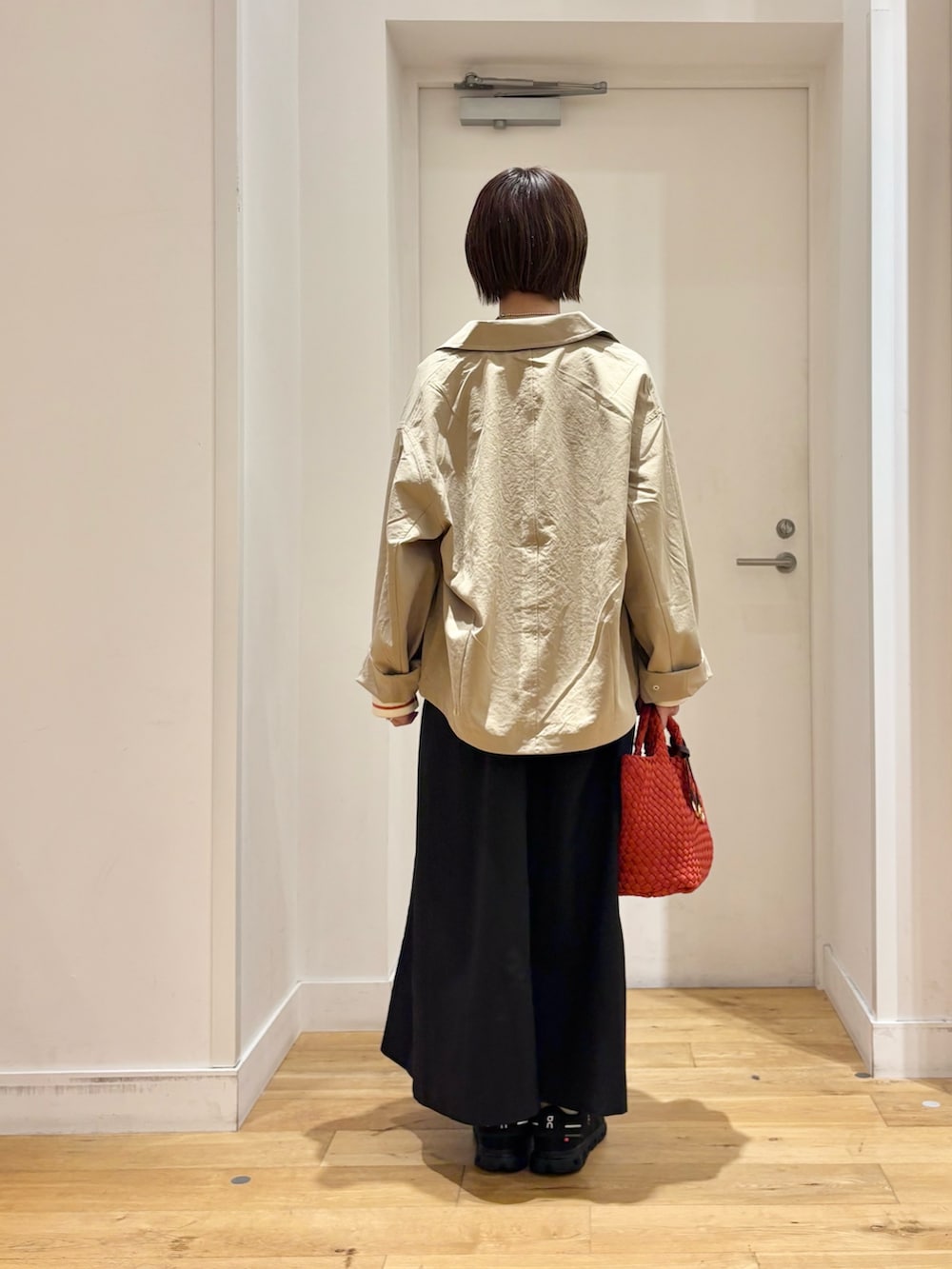 ブラック系のワンピース、ベージュ系のステンカラーコート、ホワイト系のTシャツ/カットソーを着用したレディースの秋コーディネートの7枚目の写真
