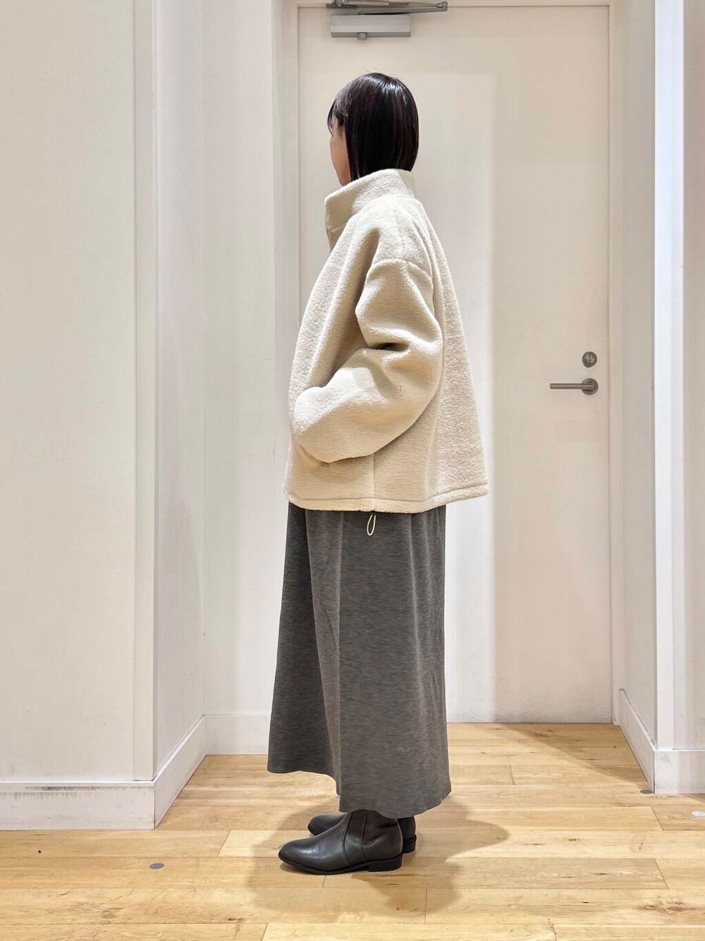 グレー系のブーツ、ホワイト系のブルゾン、グレー系のワンピースを着用したレディースの冬コーディネートの4枚目の写真