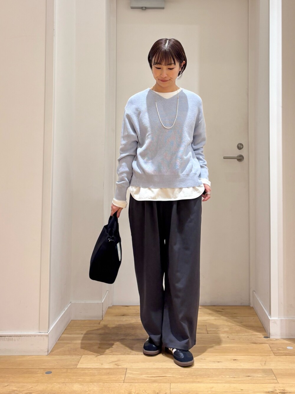 ブルー系のニット/セーター、ホワイト系のTシャツ/カットソー、ベージュ系のトレンチコートを着用したレディースの春コーディネートの7枚目の写真