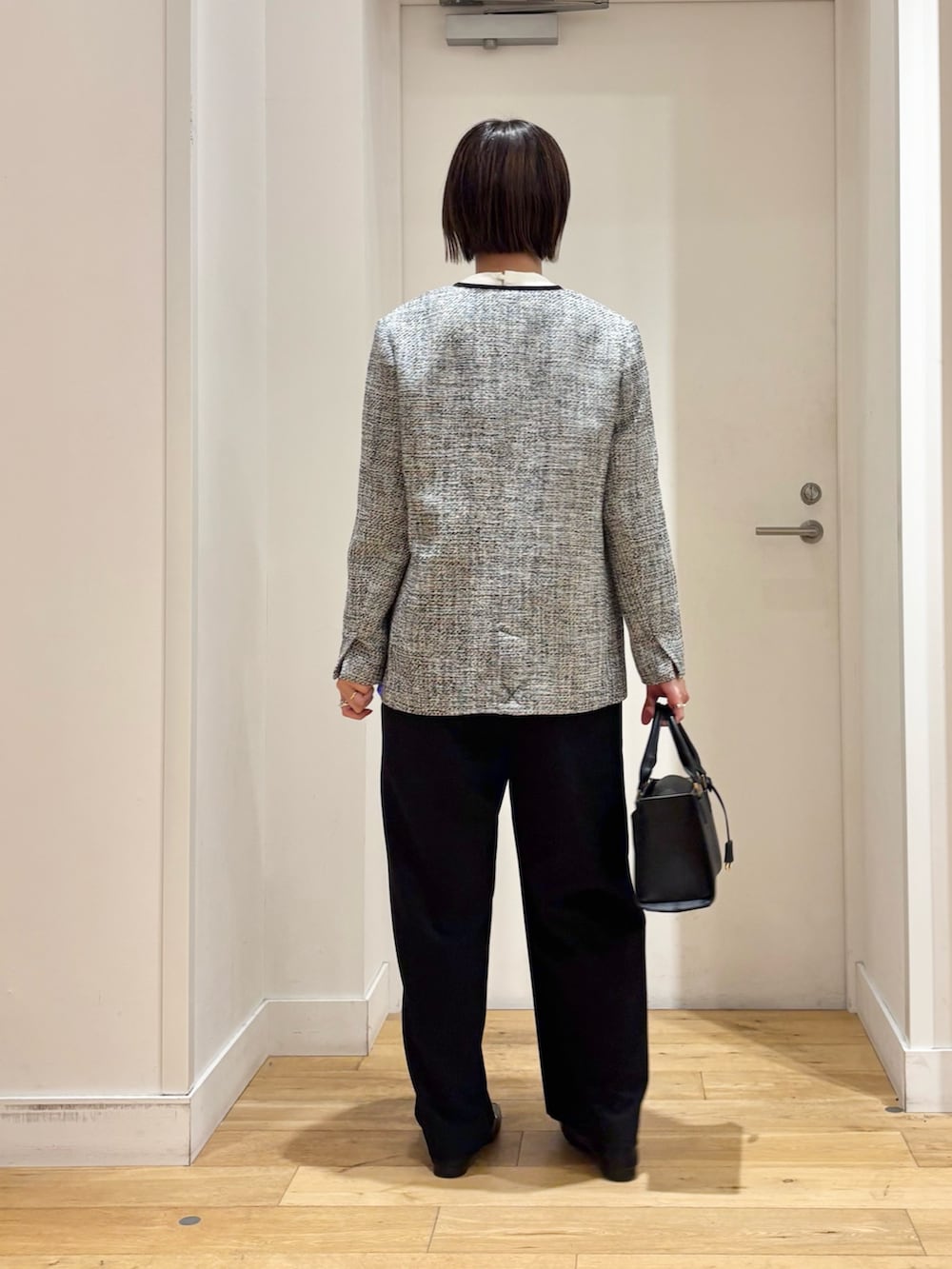 ブラック系のスーツジャケット、ホワイト系のシャツ/ブラウス、ブラック系のハンドバッグを着用したレディースの冬コーディネートの5枚目の写真