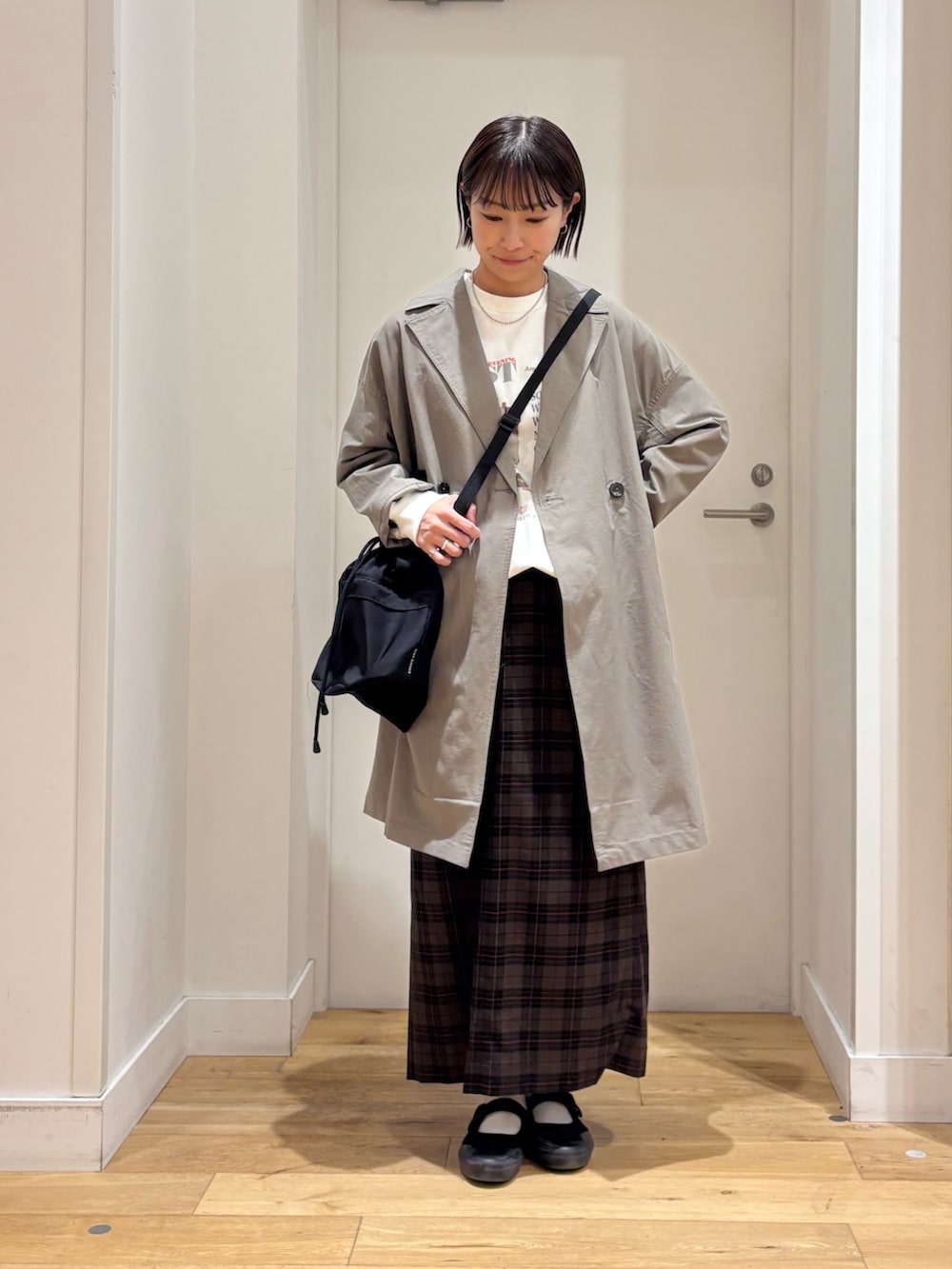 ホワイト系のTシャツ/カットソー、ベージュ系のスカート、ブラック系のショルダーバッグを着用したレディースの冬コーディネートの2枚目の写真