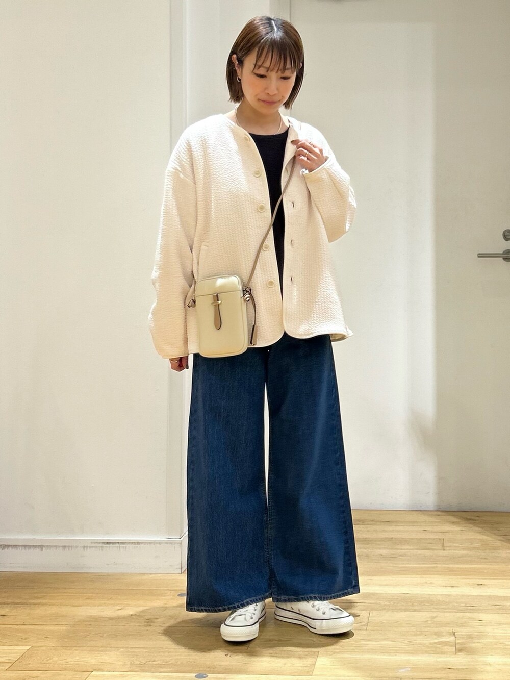 ホワイト系のノーカラージャケット、ホワイト系のショルダーバッグ、ブルー系のその他パンツを着用したレディースの春コーディネートの2枚目の写真