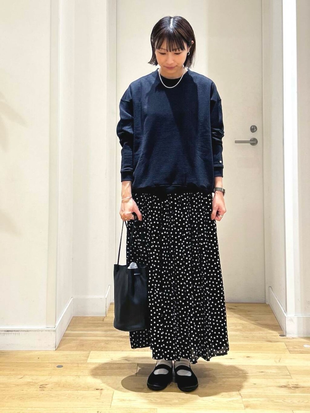 ブラック系のスニーカー、ブラック系のショルダーバッグ、ブラック系のスカートを着用したレディースの秋コーディネートの2枚目の写真