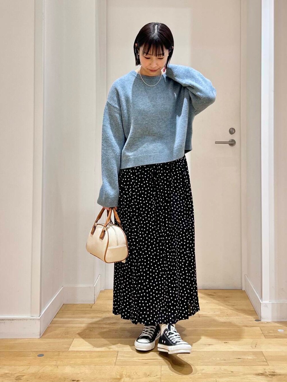 ブラック系のスニーカー、ブルー系のニット/セーター、イエロー系のボストンバッグを着用したレディースの冬コーディネートの3枚目の写真