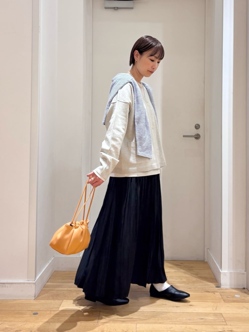 ベージュ系のTシャツ/カットソー、ベージュ系のカーディガン/ボレロ、ブラック系のスカートを着用したレディースの春コーディネートの6枚目の写真