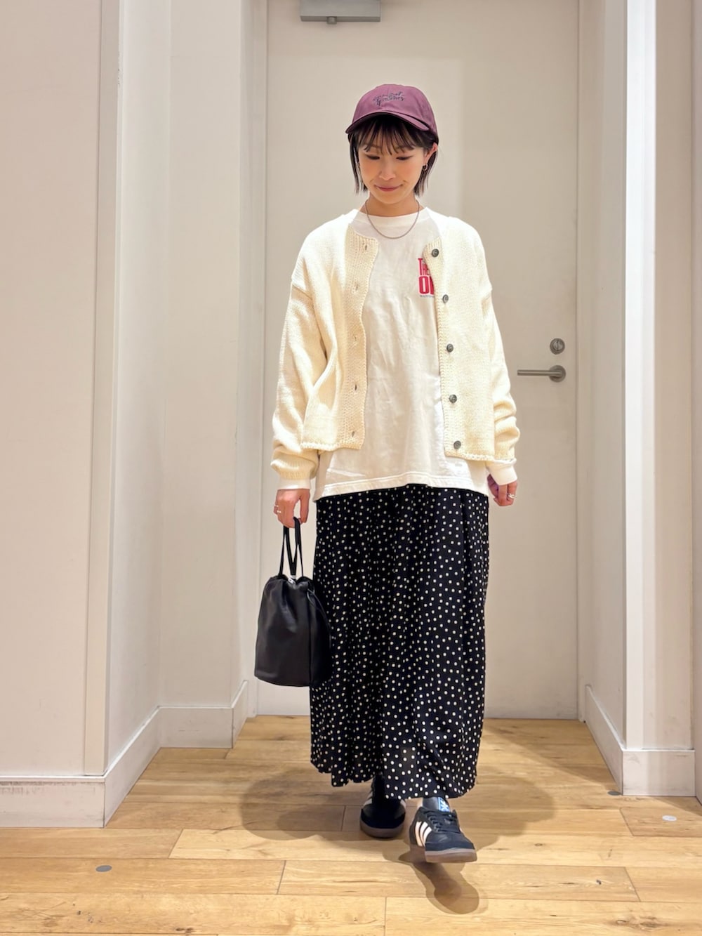 ホワイト系のカーディガン/ボレロ、ブラック系のバッグ、ブラック系のスカートを着用したレディースの冬コーディネートの2枚目の写真