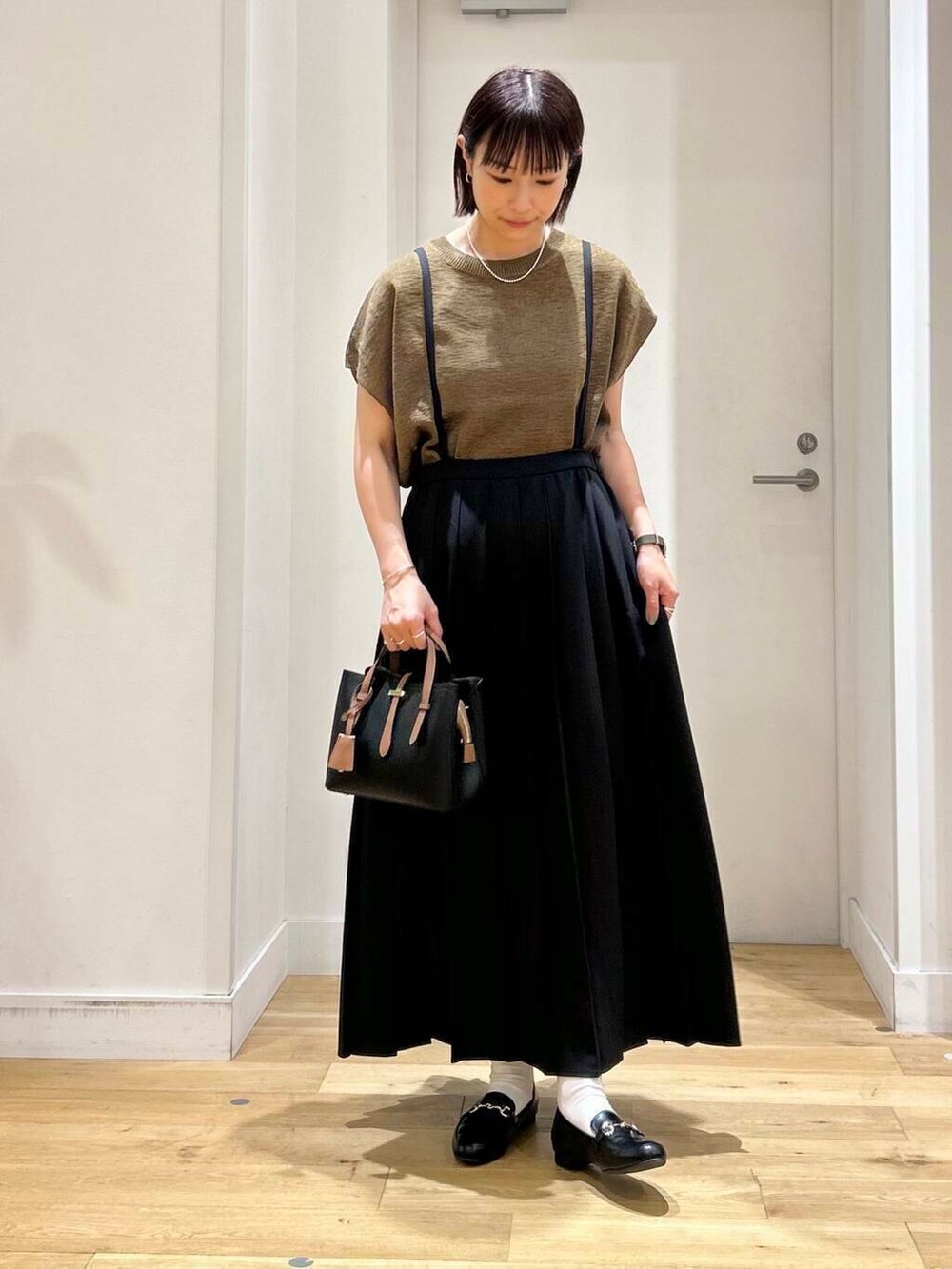 ブラック系のローファー、ブラック系のハンドバッグ、ブラウン系のニット/セーターを着用したレディースの夏コーディネートの3枚目の写真