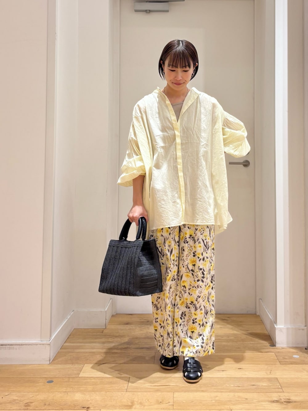 ベージュ系のタンクトップ、イエロー系のシャツ/ブラウス、ブラック系のサンダルを着用したレディースの春コーディネートの2枚目の写真