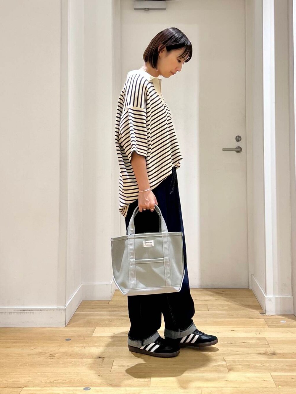 ホワイト系のニット/セーター、ブラック系のスニーカー、ブルー系のデニムパンツを着用したレディースの夏コーディネートの4枚目の写真