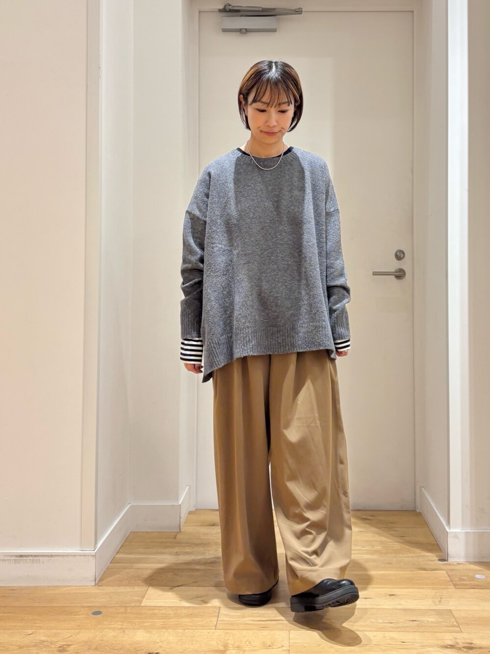 ベージュ系のその他パンツ、グレー系のニット/セーター、ブラック系のダウンジャケット/コートを着用したレディースの秋コーディネートの6枚目の写真