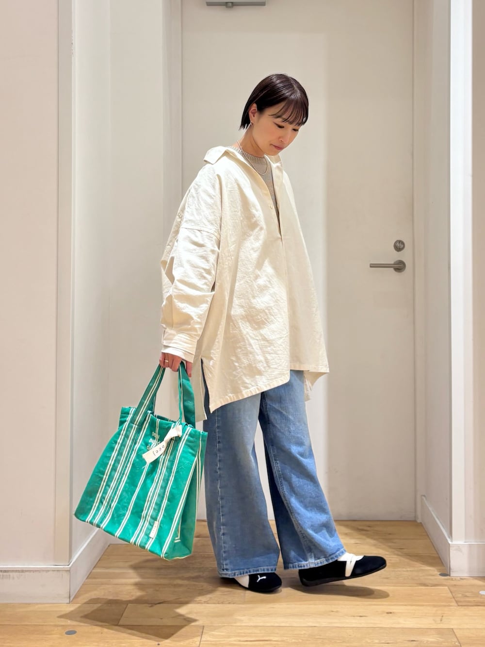 グレー系のニット/セーター、ブルー系のデニムパンツ、ブラック系のスニーカーを着用したレディースの春コーディネートの5枚目の写真