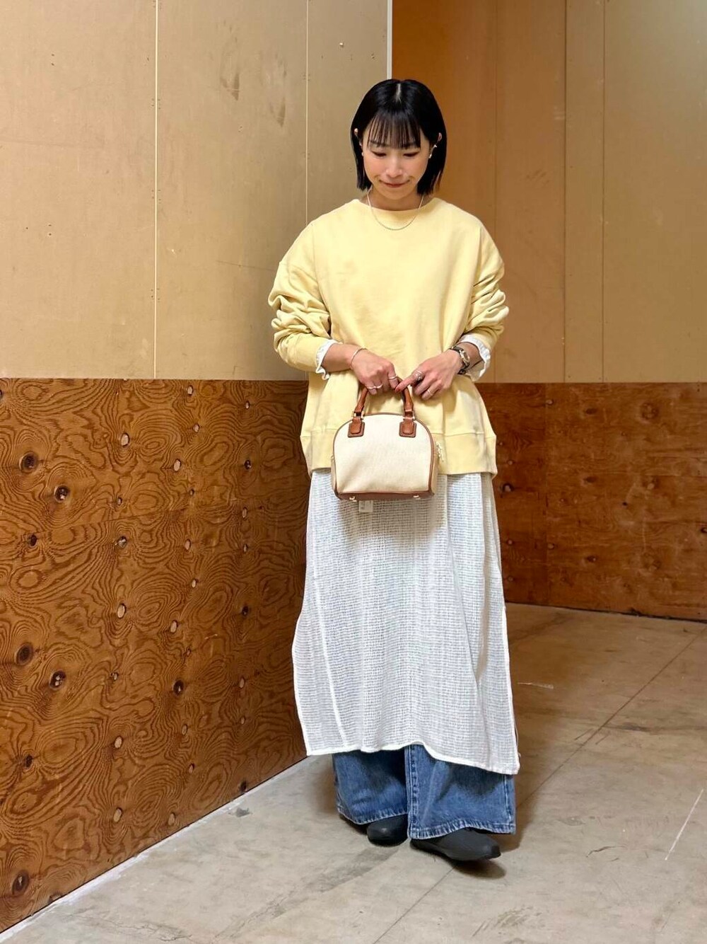 イエロー系のボストンバッグ、イエロー系のスウェット、ホワイト系のワンピースを着用したレディースの春コーディネートの3枚目の写真