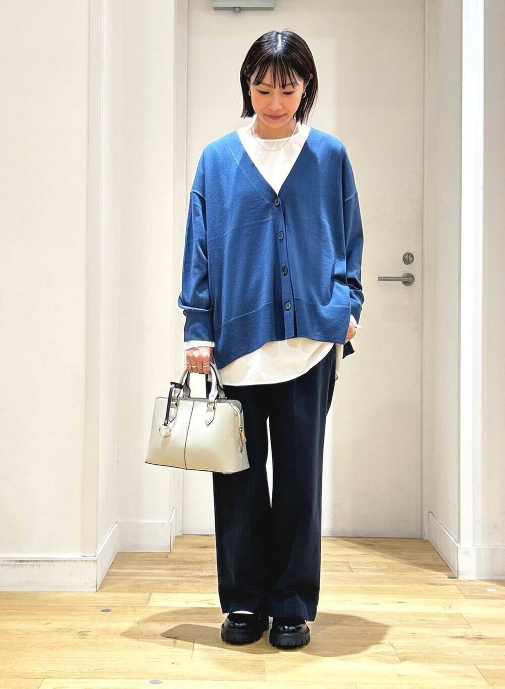ブルー系のカーディガン/ボレロ、ホワイト系のシャツ/ブラウス、グレー系のハンドバッグを着用したレディースの秋コーディネートの4枚目の写真