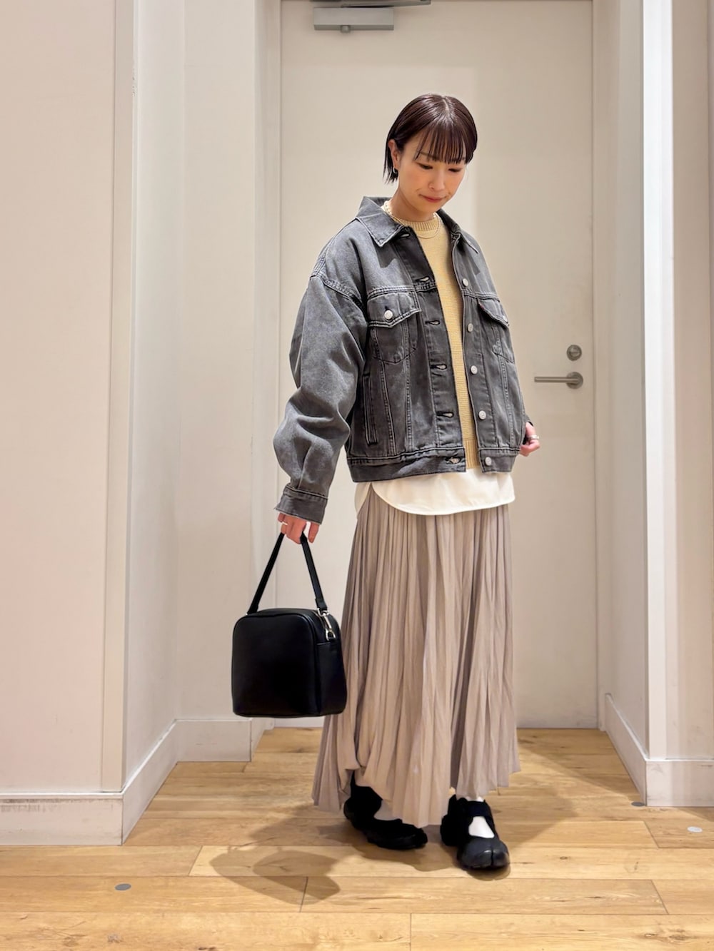 ブラック系のデニムジャケット、ベージュ系のニット/セーター、ホワイト系のTシャツ/カットソーを着用したレディースの春コーディネートの4枚目の写真