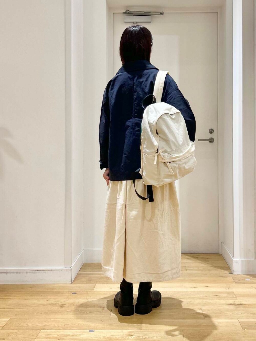 ホワイト系のバックパック/リュック、ホワイト系のTシャツ/カットソー、ブラック系のブーツを着用したレディースの秋コーディネートの5枚目の写真