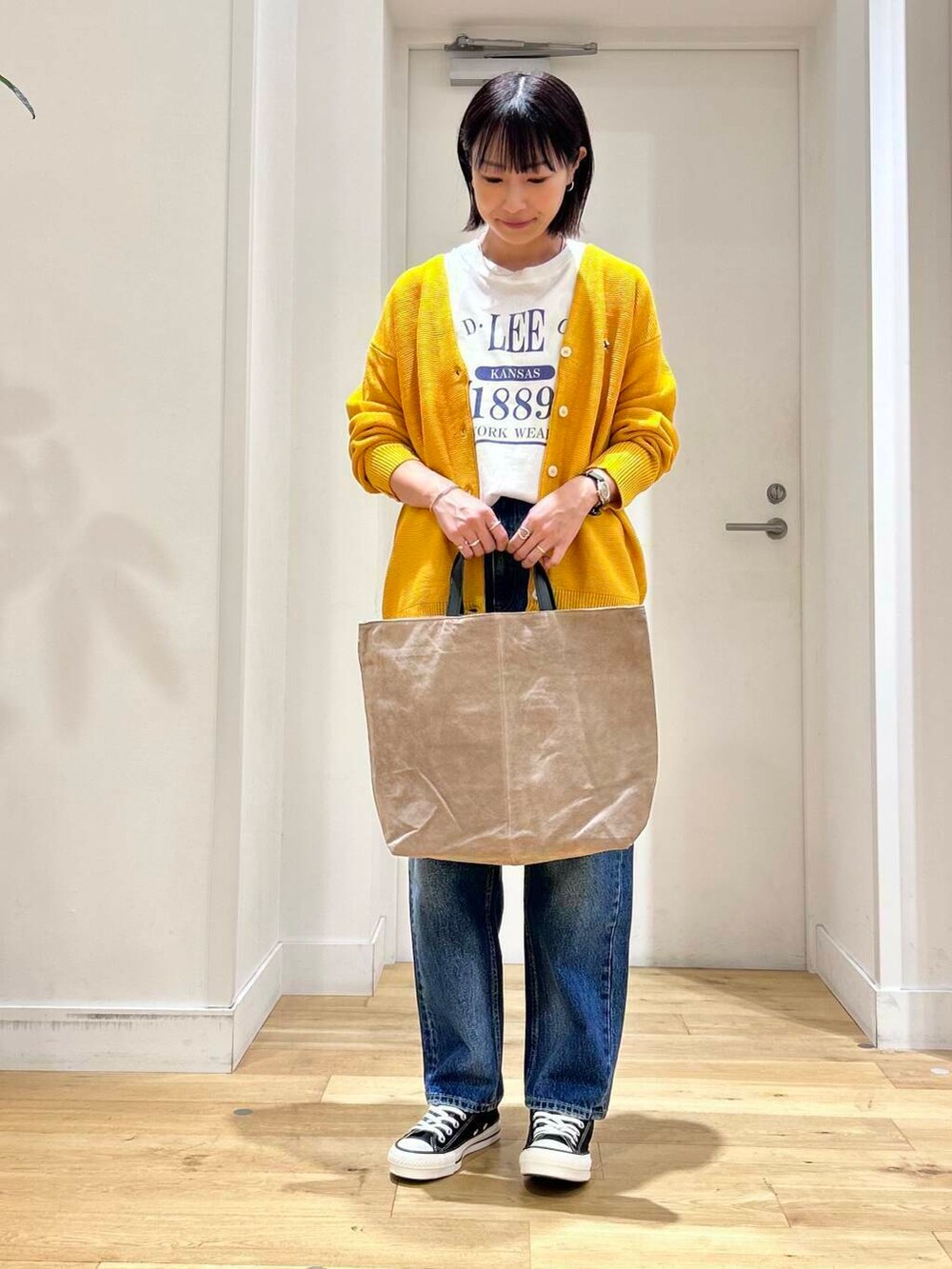 ホワイト系のTシャツ/カットソー、ブラック系のスニーカー、ベージュ系のトートバッグを着用したレディースの秋コーディネートの2枚目の写真