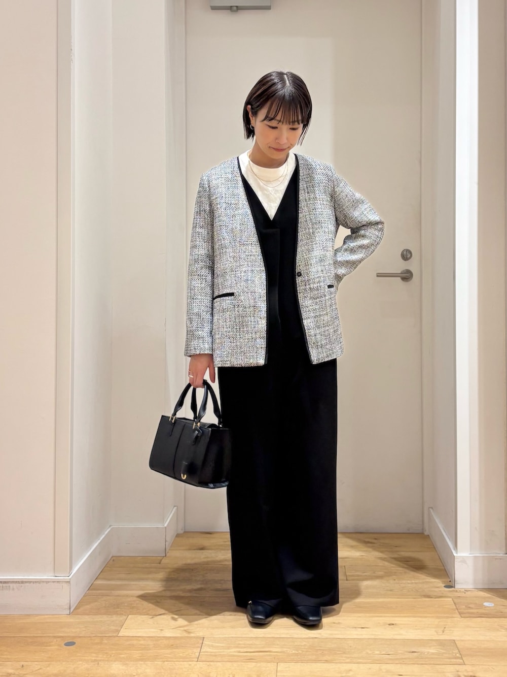 ブラック系のスーツジャケット、ホワイト系のシャツ/ブラウス、ブラック系のハンドバッグを着用したレディースの冬コーディネートの2枚目の写真