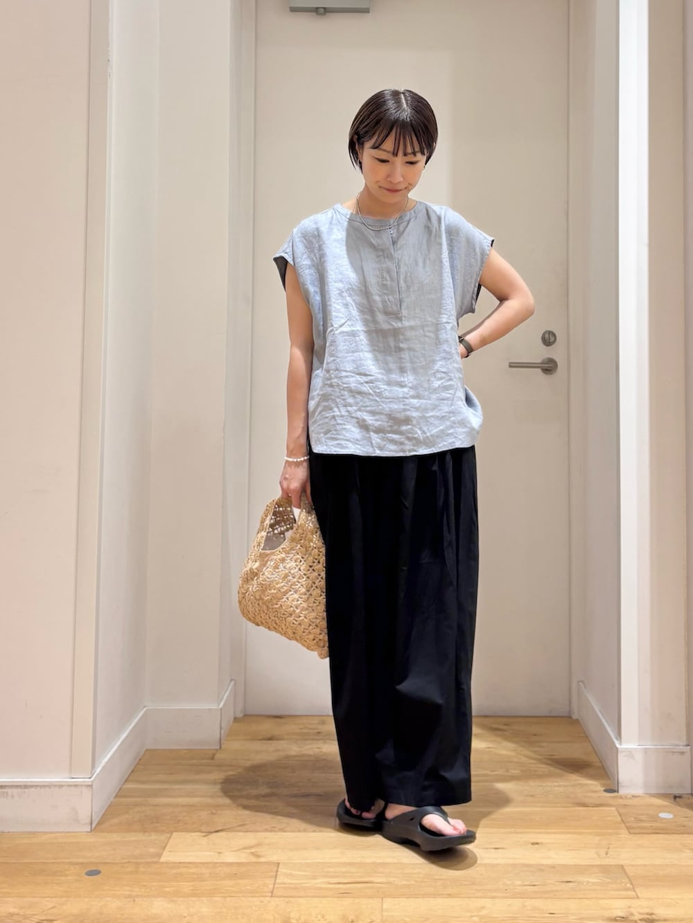 ブルー系のシャツ/ブラウス、ブラック系のその他パンツ、ベージュ系のハンドバッグを着用したレディースの夏コーディネートの2枚目の写真