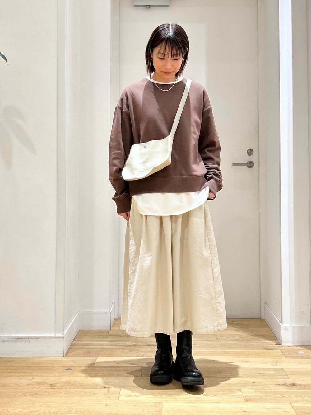 ブラウン系のスウェット、ホワイト系のスカート、ベージュ系のショルダーバッグを着用したレディースの秋コーディネートの3枚目の写真