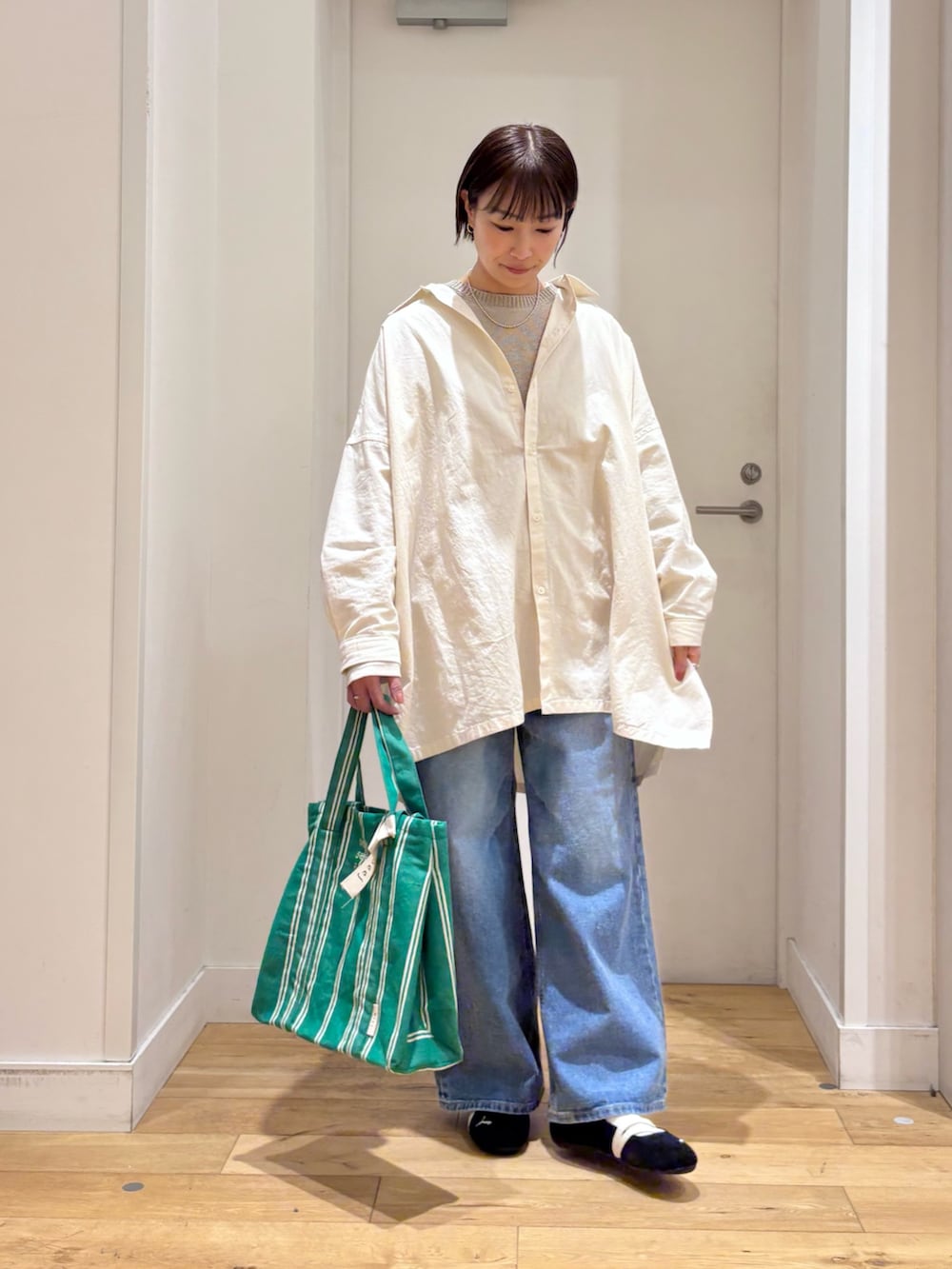 グレー系のニット/セーター、ブルー系のデニムパンツ、ブラック系のスニーカーを着用したレディースの春コーディネートの2枚目の写真