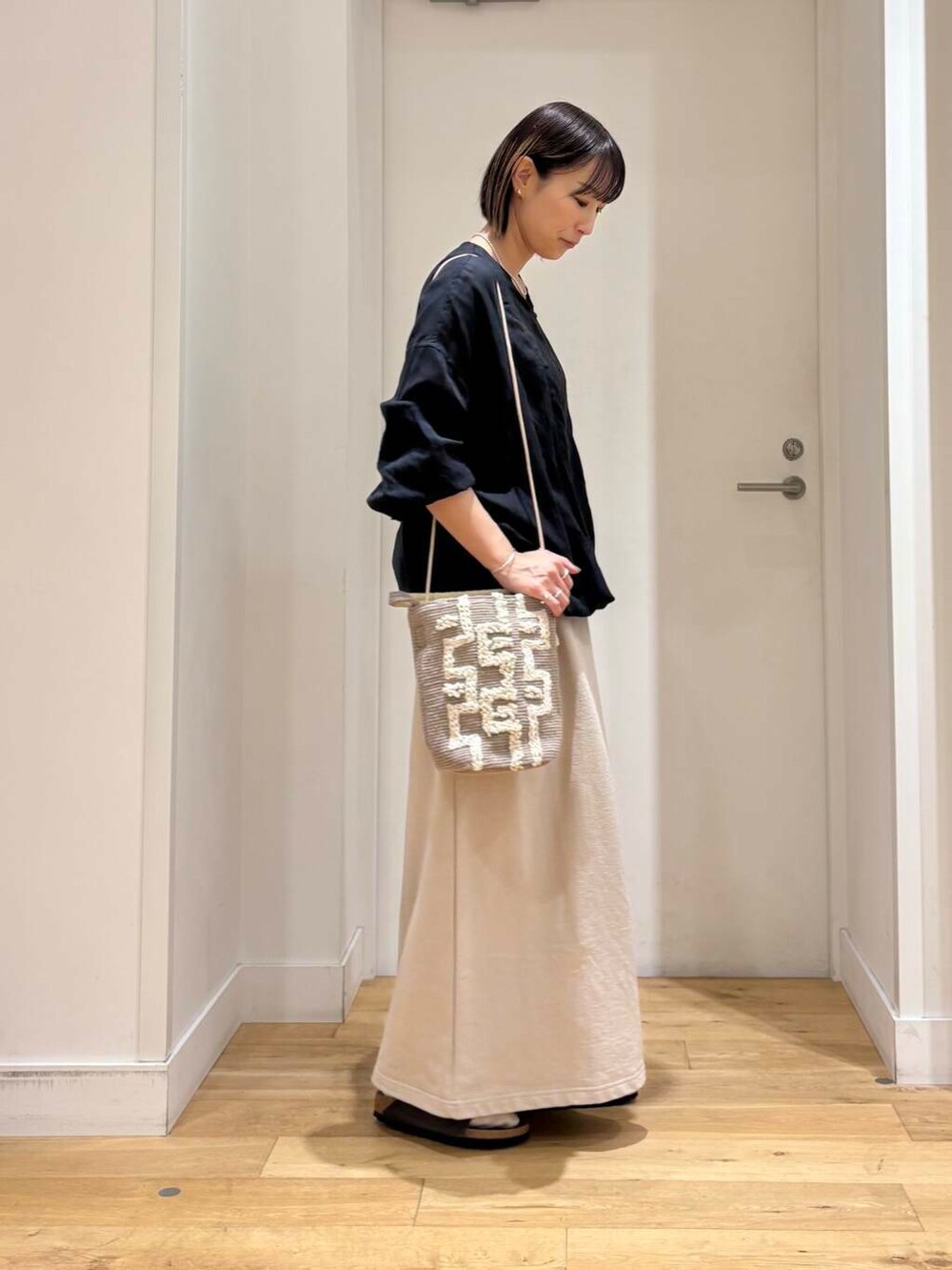 グレー系のショルダーバッグ、ブラック系のチュニック、グレー系のサンダルを着用したレディースの春コーディネートの5枚目の写真