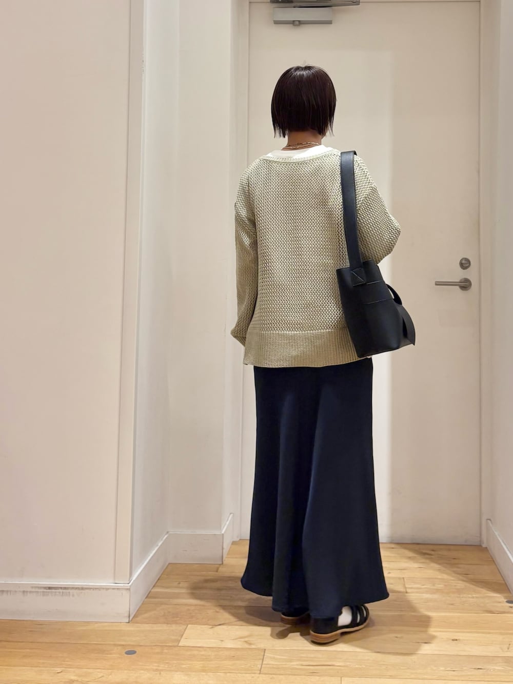 グリーン系のニット/セーター、ホワイト系のTシャツ/カットソー、ブルー系のスカートを着用したレディースの春コーディネートの6枚目の写真