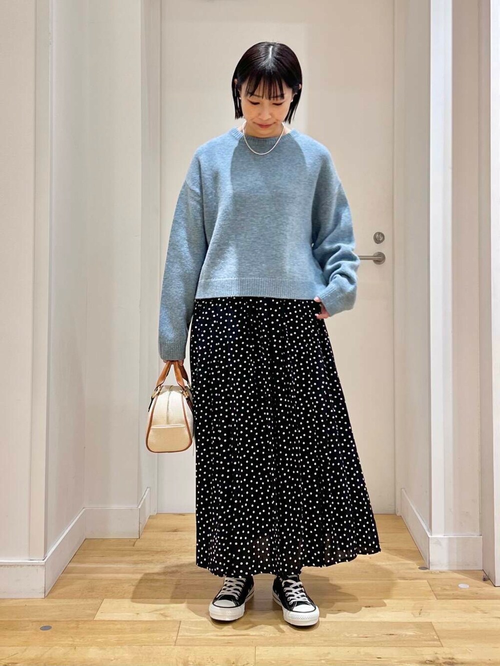 ブラック系のスニーカー、ブルー系のニット/セーター、イエロー系のボストンバッグを着用したレディースの冬コーディネートの2枚目の写真