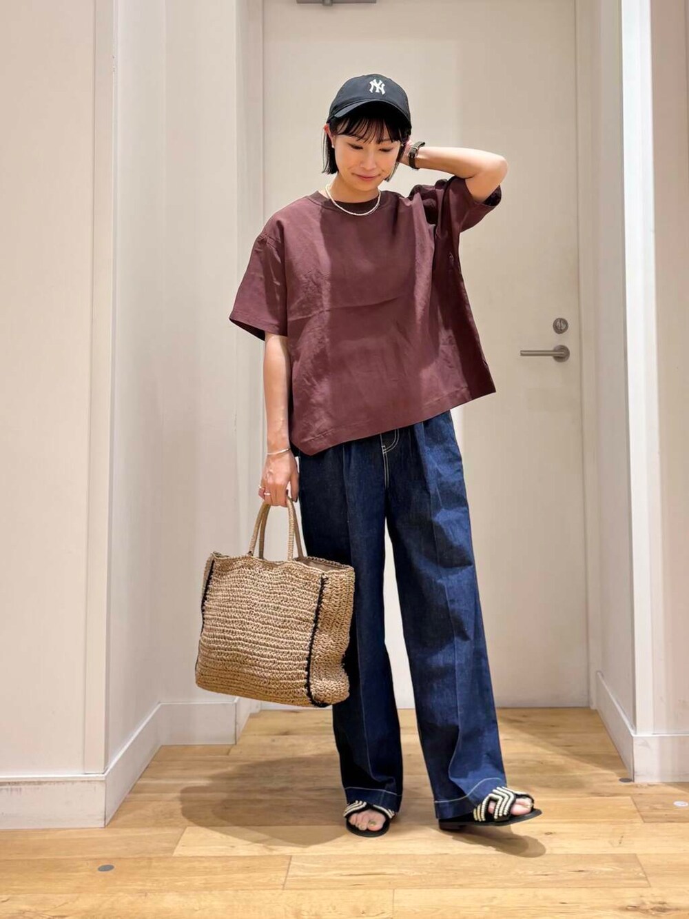 ベージュ系のトートバッグ、ブルー系のデニムパンツ、ブラック系のサンダルを着用したレディースの夏コーディネートの4枚目の写真