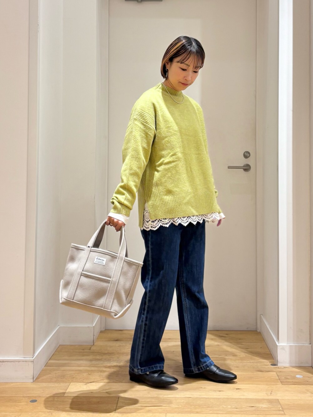 グリーン系のニット/セーター、ホワイト系のTシャツ/カットソー、ベージュ系のトートバッグを着用したレディースの冬コーディネートの3枚目の写真