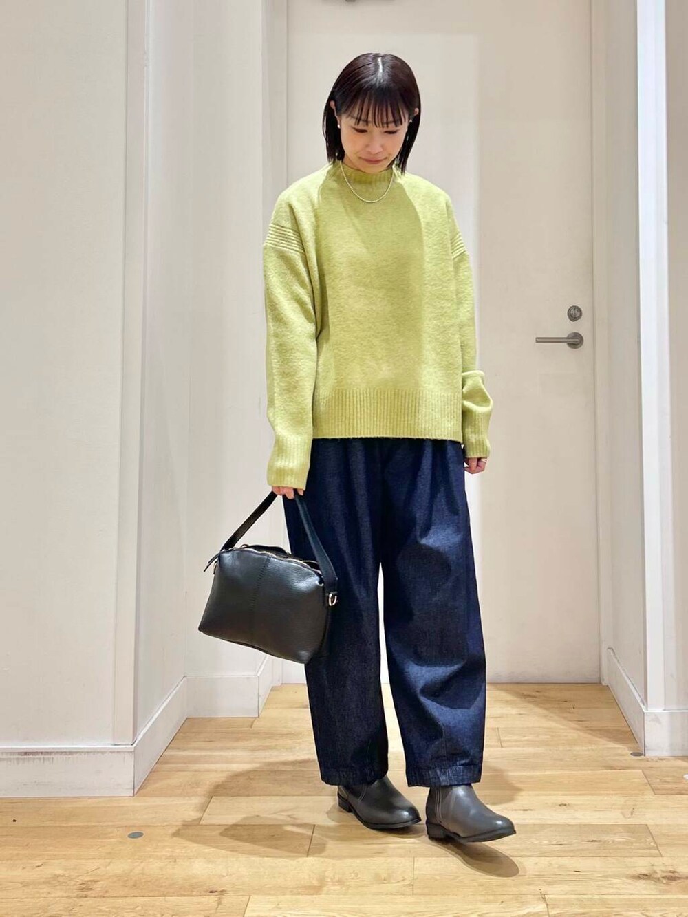 グレー系のブーツ、グリーン系のニット/セーター、ブルー系のデニムパンツを着用したレディースの冬コーディネートの2枚目の写真