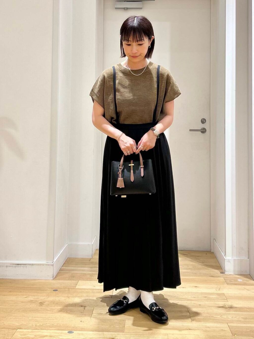 ブラック系のローファー、ブラック系のハンドバッグ、ブラウン系のニット/セーターを着用したレディースの夏コーディネートの2枚目の写真