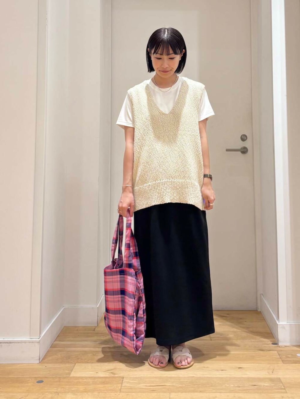 ホワイト系のサンダル、ホワイト系のTシャツ/カットソー、ブラック系のスカートを着用したレディースの夏コーディネートの2枚目の写真