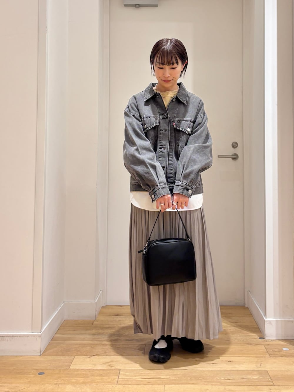 ブラック系のデニムジャケット、ベージュ系のニット/セーター、ホワイト系のTシャツ/カットソーを着用したレディースの春コーディネートの3枚目の写真