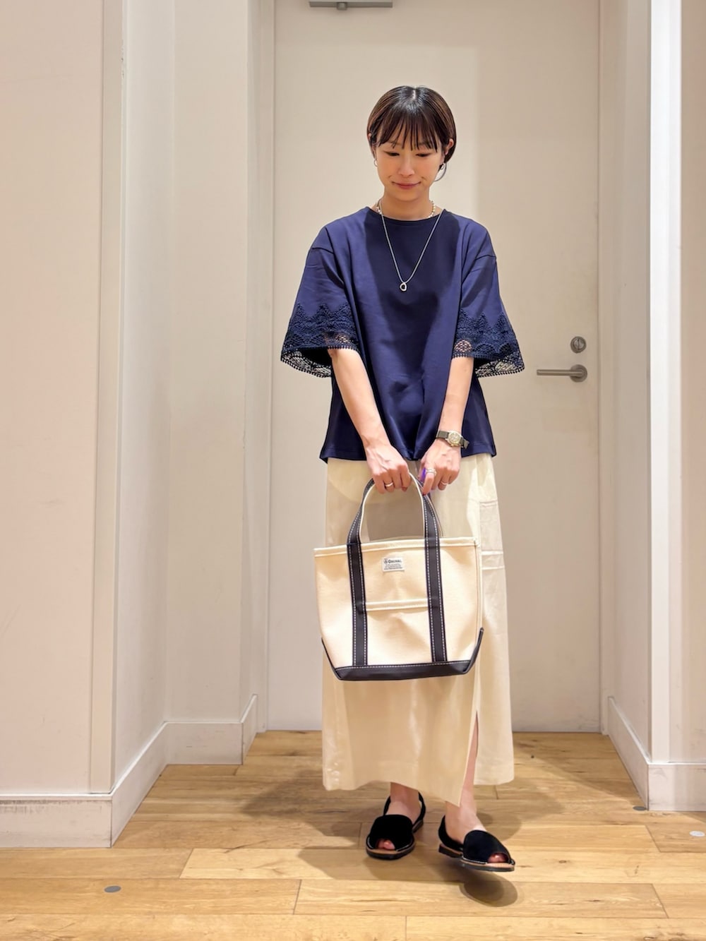 ホワイト系のトートバッグ、ホワイト系のスカート、ブラック系のサンダルを着用したレディースの春コーディネートの3枚目の写真