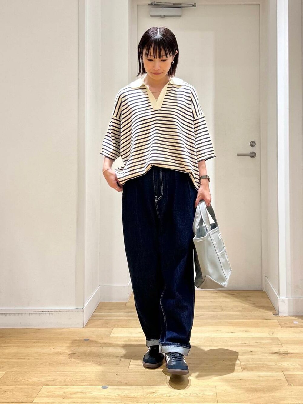 ホワイト系のニット/セーター、ブラック系のスニーカー、ブルー系のデニムパンツを着用したレディースの夏コーディネートの3枚目の写真