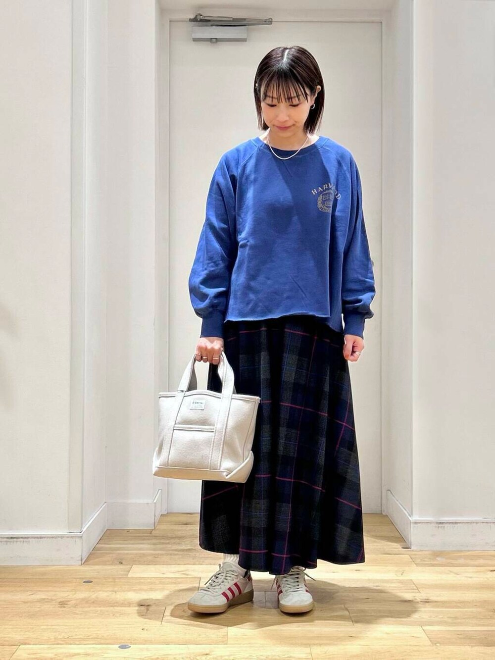 ブルー系のTシャツ/カットソー、ベージュ系のトートバッグ、ホワイト系のスニーカーを着用したレディースの秋コーディネートの3枚目の写真