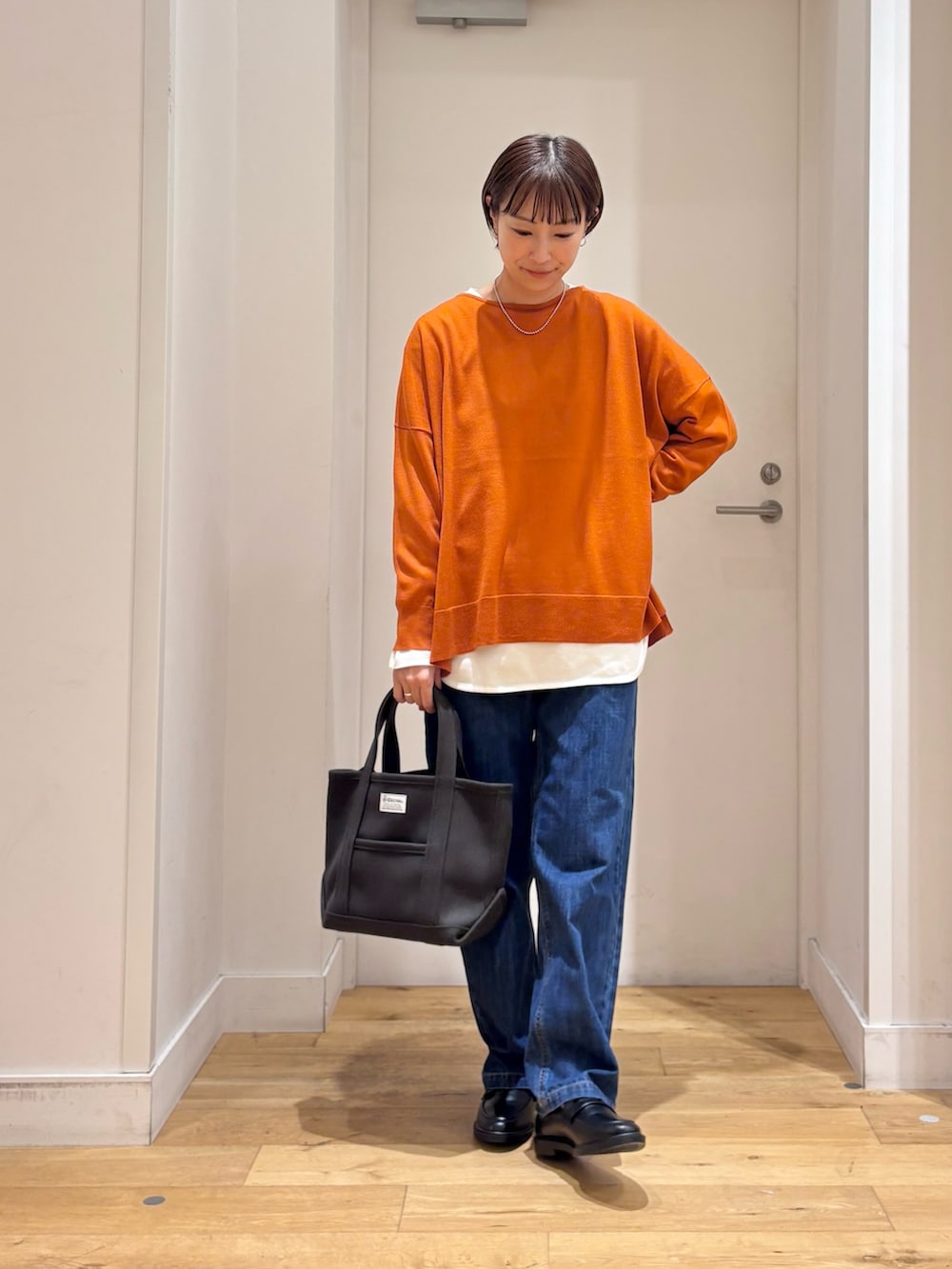 グレー系のブルゾン、オレンジ系のニット/セーター、ホワイト系のTシャツ/カットソーを着用したレディースの秋コーディネートの7枚目の写真