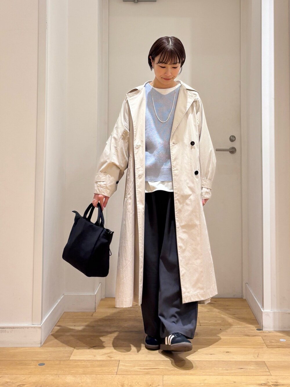 ブルー系のニット/セーター、ホワイト系のTシャツ/カットソー、ベージュ系のトレンチコートを着用したレディースの春コーディネートの3枚目の写真