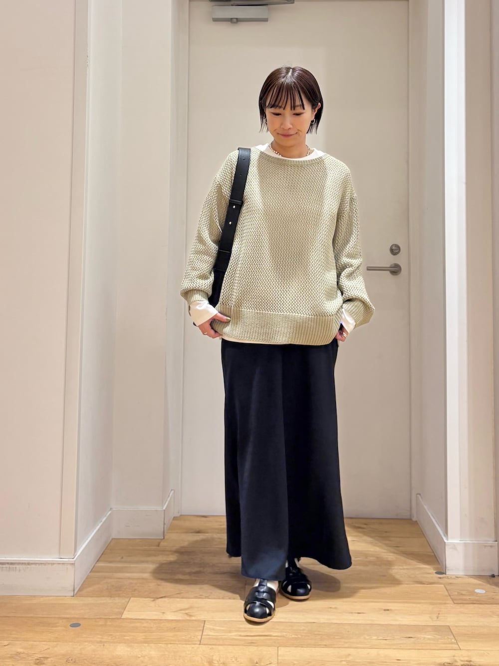 グリーン系のニット/セーター、ホワイト系のTシャツ/カットソー、ブルー系のスカートを着用したレディースの春コーディネートの3枚目の写真