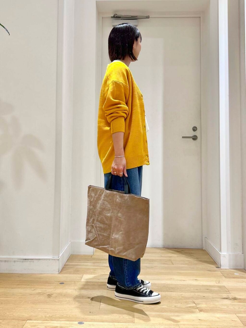 ホワイト系のTシャツ/カットソー、ブラック系のスニーカー、ベージュ系のトートバッグを着用したレディースの秋コーディネートの4枚目の写真