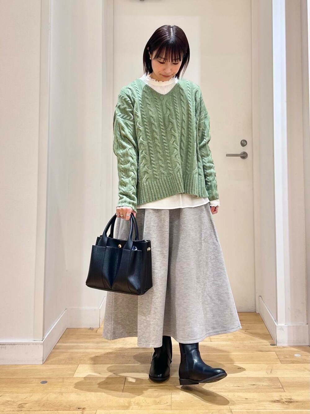 グリーン系のニット/セーター、ホワイト系のシャツ/ブラウス、ブラック系のブーツを着用したレディースの冬コーディネートの4枚目の写真